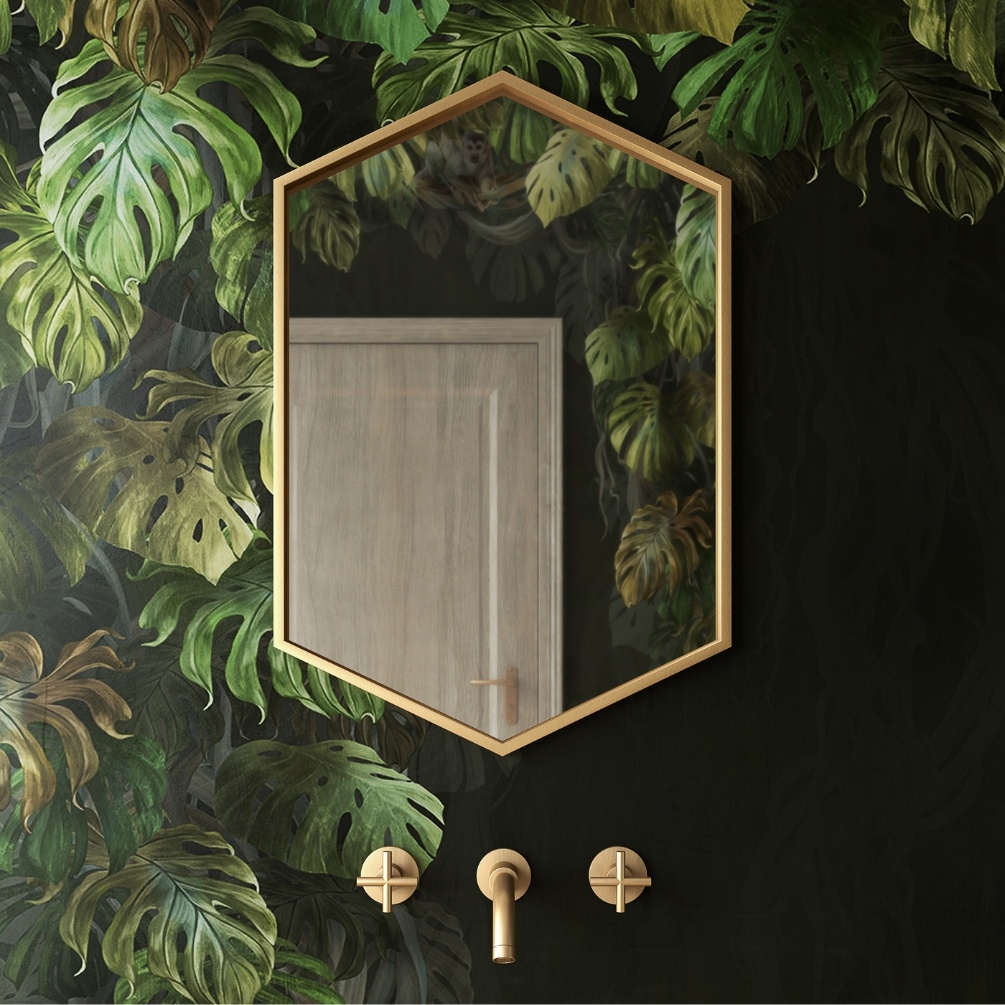 Product Lifestyle image of the Origins Living Docklands 500mm x 750mm Brushed Brass Hexagonal Mirror mounted on a nature-themed wall in-front of three taps. B375509